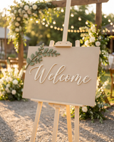 Wedding welcome sign at a reception entrance with florals and warm string lights