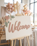 Baby shower welcome sign at the entrance to a blush and cream baby shower